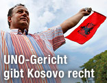 Ein Mann schwenkt eine Kosovo-Fahne