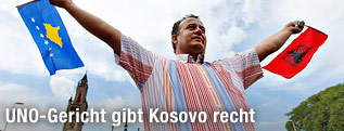 Ein Mann schwenkt eine Kosovo-Fahne