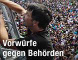 Mann flüchtet vor der Menschenmenge auf einen Zaun