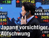 Japanischer Banker vor Anzeigetafel mit Börsenkursen