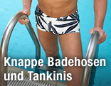 Mann in knapper Badehose steigt aus dem Pool