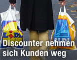 Kunde mit Lidl- und Aldi-Einkaufssackerl