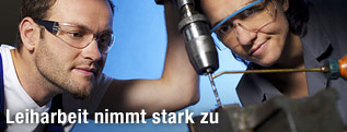 Arbeiter sehen konzentriert zu Bohrer