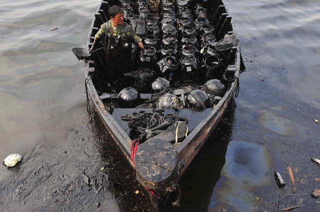 Ein Fischer transportiert Ölfässer auf einem Boot
