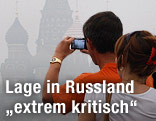 Touristen fotografieren die in Rauch gehüllte Basilius-Kathedrale in Moskau