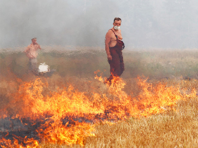© Reuters/Mikhail Voskresenskiy Mann steht im brennenden Feld