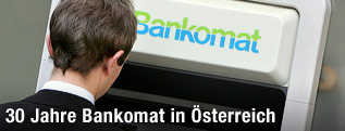 Ein Kunde hebt von einem Bankomat Bargeld ab.