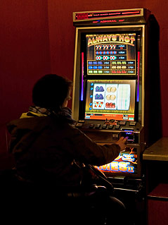 Person sitzt vor einem Spielautomaten