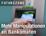 Jemand steckt Bankomatkarte in bankomatschlitz