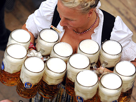 Eine Kellnerin am Münchner Oktober trägt zahlreiche Bierkrüge.
