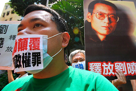 © AP/Vincent Yu Demonstrant in Hongkong mit beschriftetem Mundschutz und einem Plakat von Liu Xiabao im Hintergrund