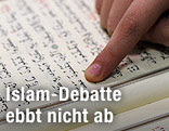 Finger f&auml;hrt &uuml;ber eine Koranseite