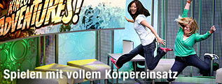 Zwei Frauen springen beim Spielen mit Microsoft Kinect in die Luft.