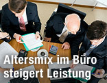 Kollegen unterschiedlichen Alters sitzen gemeinsam an einem Bürotisch
