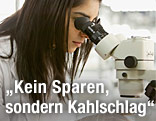 Junge Frau blickt in ein Mikroskop
