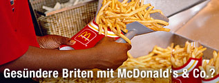 Angestellter befüllt Pommes-Frites-Schachtel