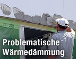 Arbeiter schmiert Verputz auf auf ein mit Styropor isoliertes Haus