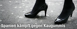 Damenschuh auf einer mit Kaugummis vollkeklebten Straße