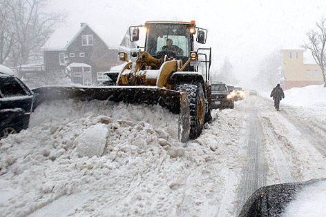 © AP/David Duprey Ein Bagger räumt Schnee von der Straße.