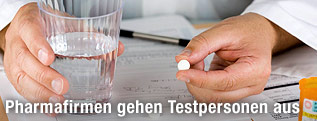 Ein Arzt mit einem Glas Wasser und einer Tablette in der Hand