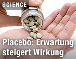 Tabletten werden in eine Hand geleert.