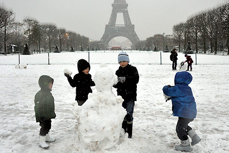 Kinder bauen Schneeman vor Eiffelturm