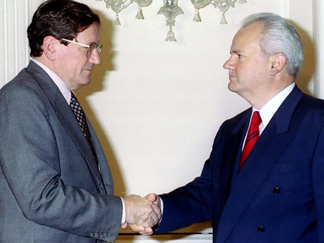 © Reuters/Emil Vas Richard Holbrooke schüttelt mit eiserner Miene dem ehemaligen jugoslawischen Staatspräsident Slobodan Milosevic die Hand