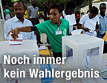 Wähler in Haiti, die gerade ihre Wahlkarte in die Urne werfen