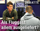 Passagiere sitzen in einem Flughafen-Terminal auf dem Boden und warten