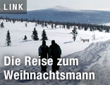 Zwei Menschen spazieren durch eine Winterlandschaft in Lappland