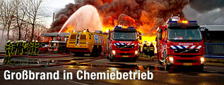Feuerwehrwagen stehen vor einer brennenden Fabrik