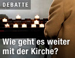 Person z&uuml;ndet Friedenslichter in einer Kirche an