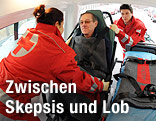 Rotes Kreuz Mitarbeiter heben Patienten ins Auto