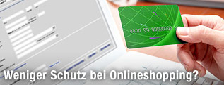 Hand hält Kreditkarte vor Computer