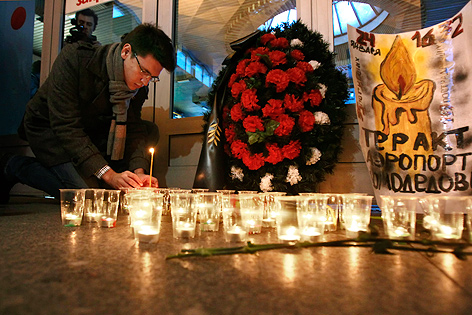 © AP/Dmitry Lovetsky Mann legt ein Kerzenlicht zu anderen Kerzen und Blumen