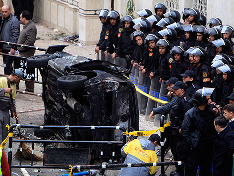 © Reuters/Amr Abdallah Dalsh Polizisten hinter einer Absperrung sichern die Anschlagstelle mit einem zerstörten Auto.