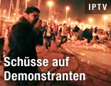 Mann Hk&auml;lt sich Tuch vor dem Mund, Demonstranten laufen vor Sch&uuml;ssen davon