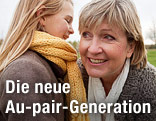 Kind flüstert einer älteren Au-pair-Frau etwas ins Ohr