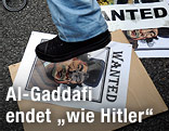 Demonstrant steht auf einem Bild von Al-Gaddafi