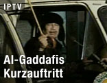 Der libyische Staatsf&uuml;hrer Muammar al-Gaddafi spricht aus einem Auto mit einem wei&szlig;en Regenschirm in der Hand