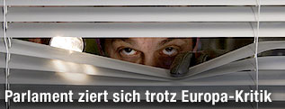 Mann versteckt sich hinter Jalusien