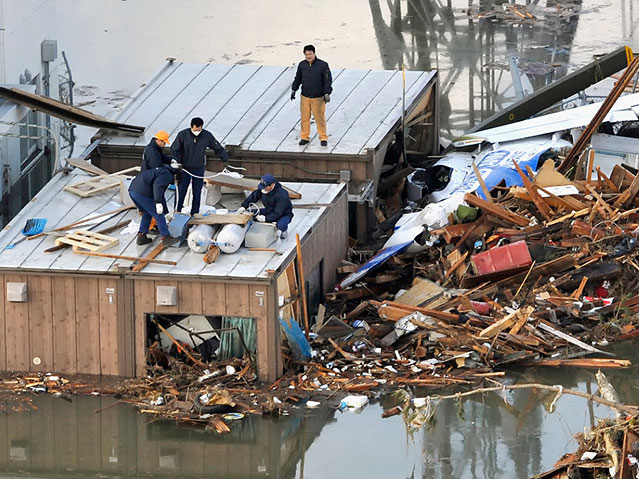 © Reuters/Kyodo Menschen bauen am Dach eines Hauses ein Floß aus den Trümmern