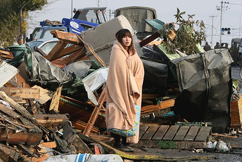 Frau in Ishimaki vor den Trümmern der Erdbebenkatastrophe