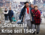Menschen vor Tr&uuml;mmernin der japanischen Stadt Minami Sanriku