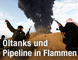 Rebellen in der Wüste, dahinter Rauchwolken