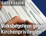 Hand unterschreibt Volksbegehren f&uuml;r Kirchenprivilegien