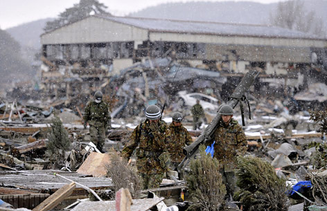 Zwei Soldaten gehen zwischen Trümmern in der Stadt Ishinomaki