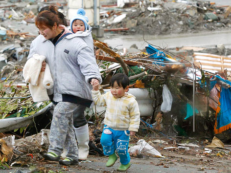 © Reuters/KYODO Kyodo Frau mit zwei Kindern geht durch Trümmer