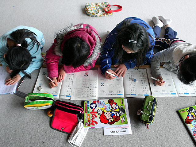 © AP/Tokyo Shimbun, Masato Sawada Kinder schreiben in Schulbüchern.