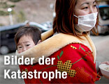Frau mit Schutzmaske und Kind am Rücken